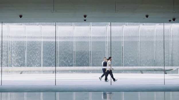 Business professional in a modern office thoughtfully analyzes a complex network diagram on a glass wall, representing mod...