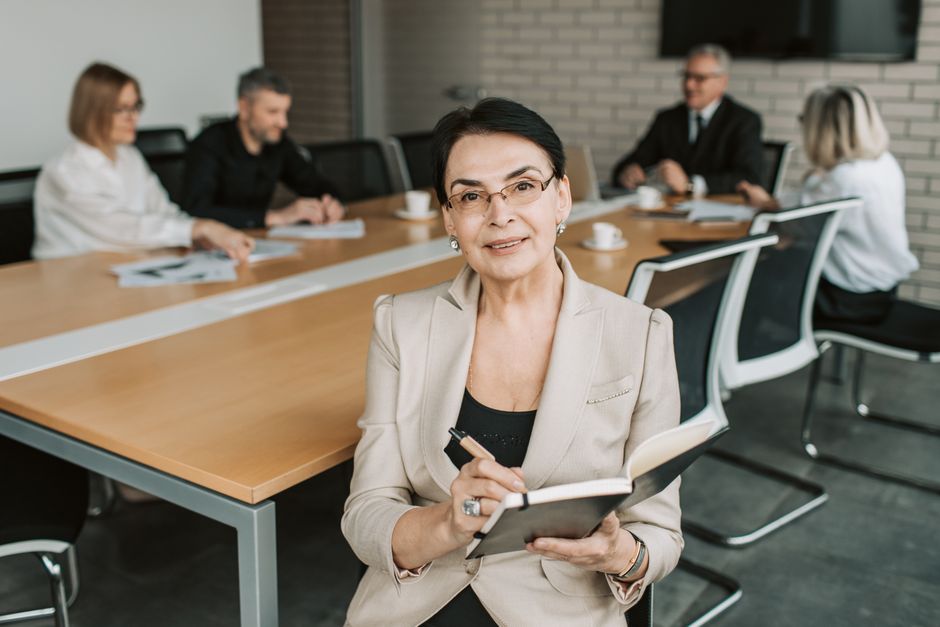 A person in business attire sits alone at the end of a long, empty boardroom table, conveying the sense of isolation and pressure that can accompany a high-status career.