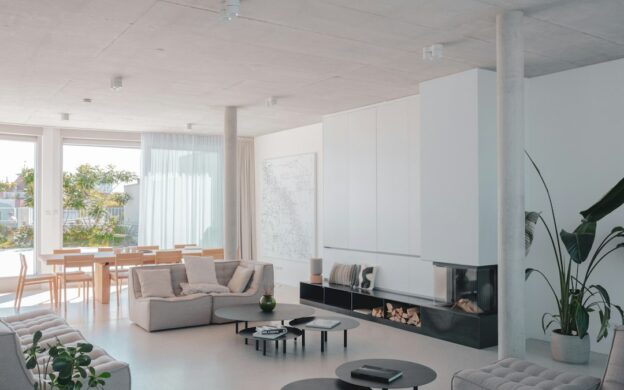 Bright, airy interior of a modern vacation home with minimalist furniture and a large window looking out onto a scenic view.