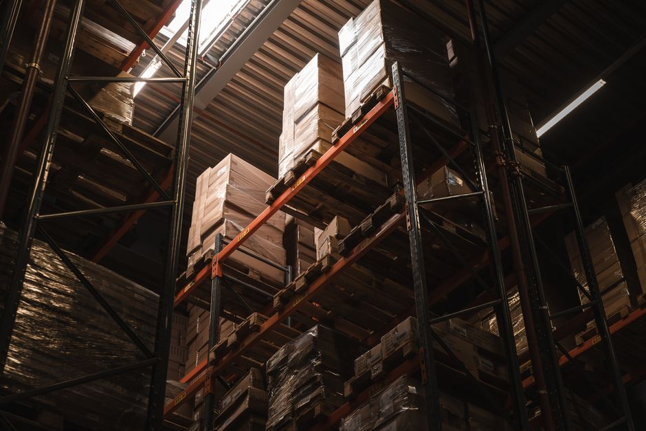 The interior of a massive, modern logistics warehouse with tall, neat shelves stretching into the distance, illustrating the scale of e-commerce infrastructure.
